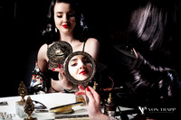 Boudoir photo in the old Hollywood style of a woman at her boudoir table holding a mirror..