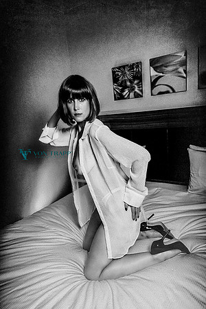 Sexy boudoir photo of a woman in a sheer white shirt and fuck me stilettoes, flashing a boob.