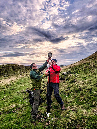 Behind the scenes photo of two men setting up a strobe for a photoshoot along Hadrian's Wall, England.