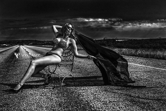 Glamour photo of a hot woman in a sexy bikini, sitting in a chair on a West Texas road.