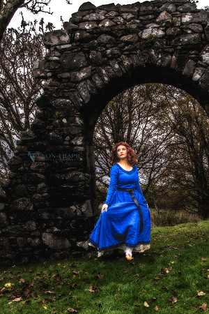 Fine Art color photo of a woman in period clothing walking through a stone arch of a Scottish castle in the highlands.