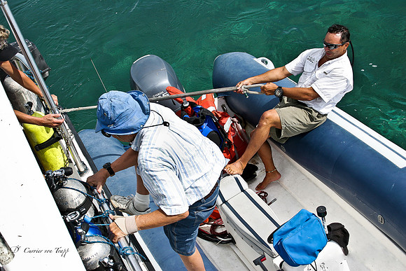 Photo of a man boarding a boat from a rubber boat.