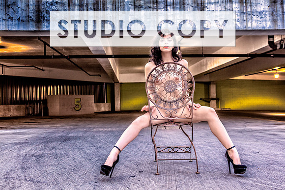 Color glamour nude photo of a hot young woman in a public parking garage.