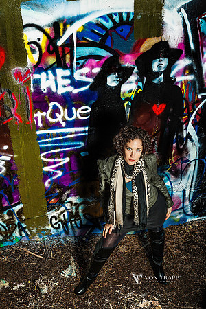 Urban Glamour photo of a stylishly dressed and sexy woman posed next to a graffitied wall.