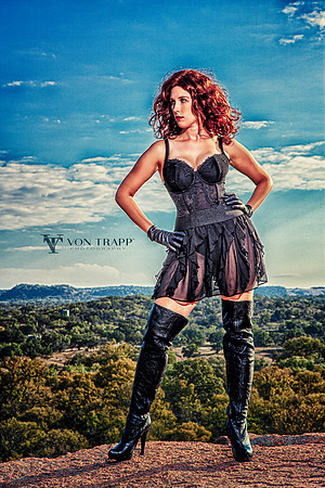 Pin up photo of a sexy redhead in thigh high boots and lingerie, standing on a cliff in Texas.
