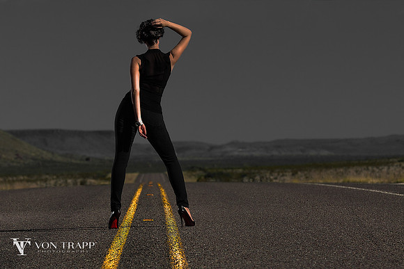 Fashion glamour photo of a leggy woman standing on a road.