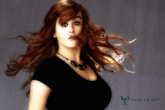 Glamour portrait of a busty young red head woman.