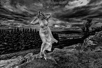 Fine art photo of a sexy woman dressed in a sheer gown, posed on a kno;; in Scotland.