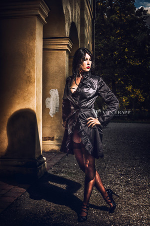 Edgy fashion nude of a dark beauty in a long coat and heels flashing her stocking tops in public.at a palace in Germany.