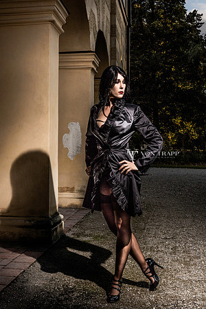 Erotic photo of a sexy woman in a trench coat, stockings, and stilettoes flashing at a castle in Germany.