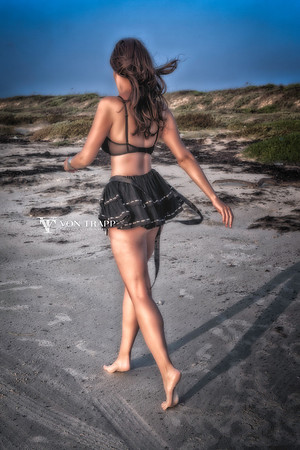 Outdoor Boudoir photo of a sexy woman strolling on a Texas beach in a short-short skirt and bra.