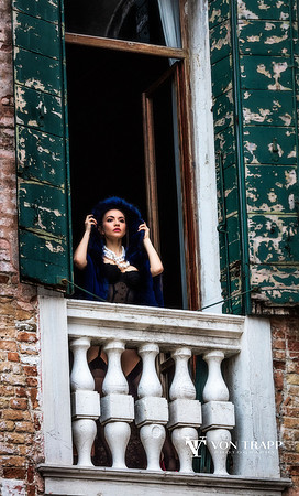 Fashion photo of a woman at a window of a palazzo in Venice, Italy.