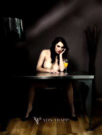 Fashion nude photo of a woman sitting at a desk.