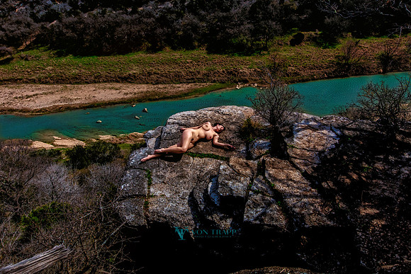 Art nude photo of a woman reclined on a cliff edge overlooking a river in Texas.
