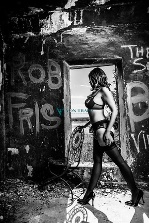 Lingerie glamour photo of a woman in an abandoned building with graffiti on the walls.
