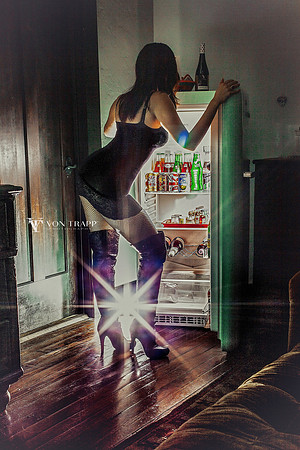 Photo of a sexy woman in a slip, fishnet pantyhose and thigh-high come fuck me boots, bending over looking into a refrigerator.