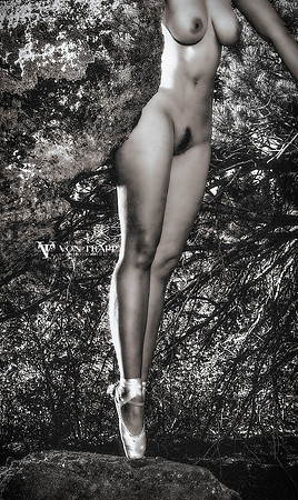 Fine art nude photograph of a woman outdoors wearing toe shoes and standing en pointe on a granite stone outdoors.