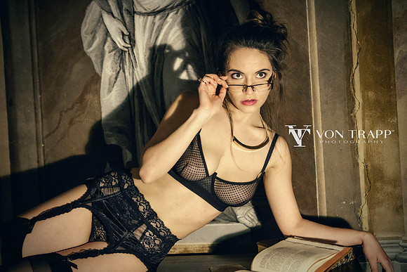 Sexy woman wearing black lace lingerie and glasses in a frescoed Venetian palazzo.