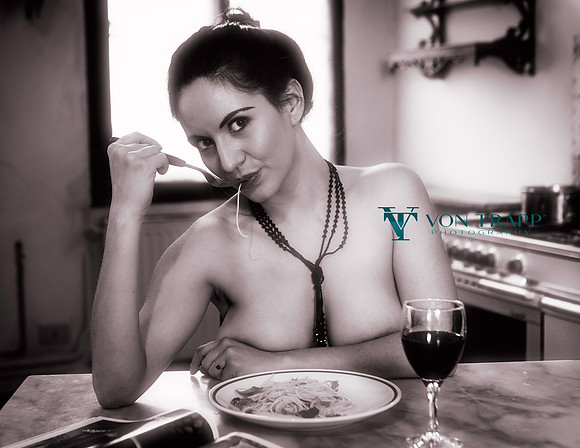 Fashion editorial image of a nude woman eating pasta in a Venetian palazzo's kitchen.