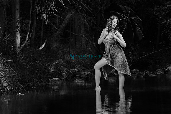 Emotive photo of a beautiful woman holding an umbrella while standing in a stream in Texas.