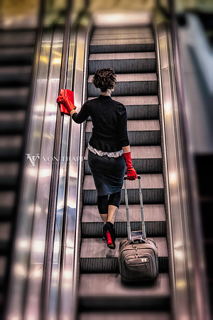 Photo of a stylish woman traveler on an airport escalator.