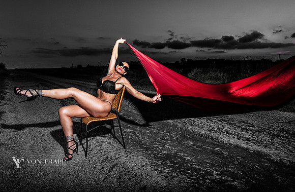 Fashion photo of a woman wearing bra, panty and heels, seated in a chair on a road in Texas.