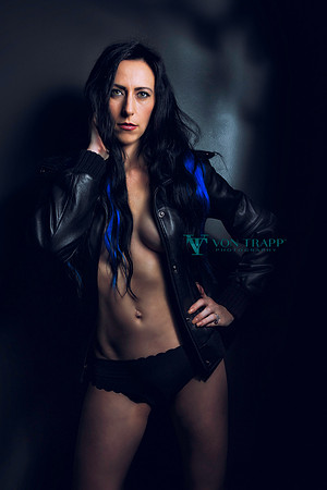 Glamour photo of a hot topless woman in a leather jacket and panties.