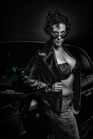 Glamour photo of a busty woman in a lace be a and leather jacket, flashing outdoors.