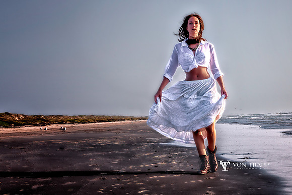 Emotive glamour photo of a sexy woman dressed in sheer white, strolling on a Texas beach in the early morning.
