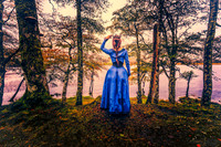 Color Fine Art photo of a woman in a period Celtic dress and crown, posed in front of a Scottish Loch.