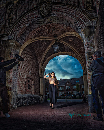 Behind the scenes photo taken in Naarden Holland of a photographer and his assistant photographing a topless woman outdoors.