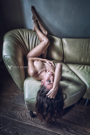 Art nude photo of a leggy Dutch woman on a sofa with her legs up.