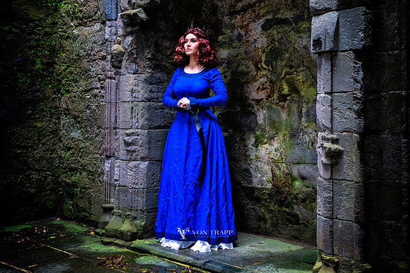 Fine art cosplay photo of a woman in period Gallic dress and a crown, posed in a Scottish castle.