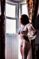 Art nude photo for sale of a busty redhead standing in a dormer window of a Scottish building in Ft. William, Scotland.