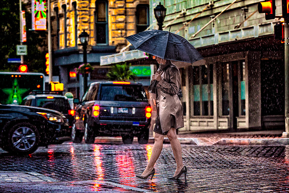 Glamour photo of a rainy day in San Antonio, with a woman walking holding an umbrella.