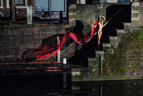 Art nude of a Dutch woman standing by a canal in Gouda Holland at nighttime.