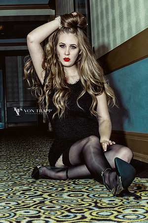 Fashion-Glamour photo of a sexy young blonde woman sitting on the floor in a short dress.