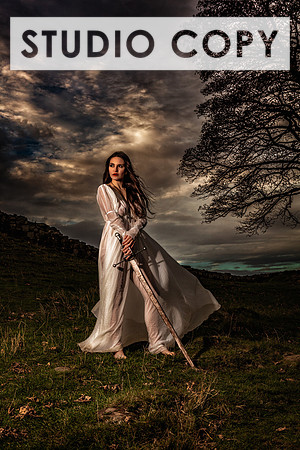 Fine art photo of a sexy woman wearing a vintage-inspired chemise, holding a Claymore sward, posed in Scotland at Hdrian's Wall.