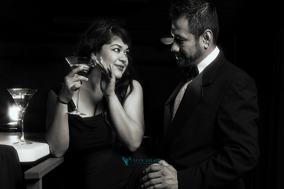 Glamorous engagement photo of a couple in formal wear having a cocktail.