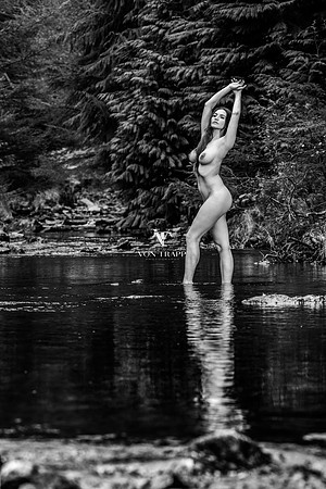 Art nude photo of a busty woman standing in a river in the Lake District of England.