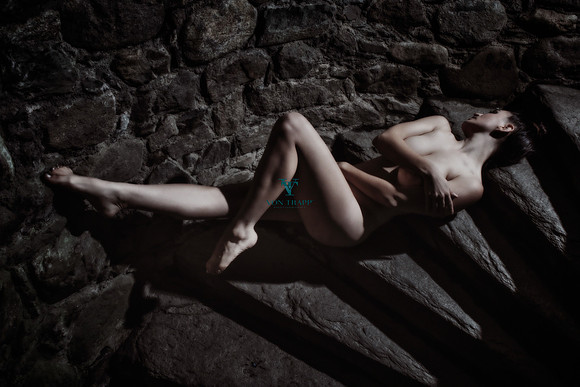 Art nude photo of a woman reclined in a spiral staircase of a Scottish castle.