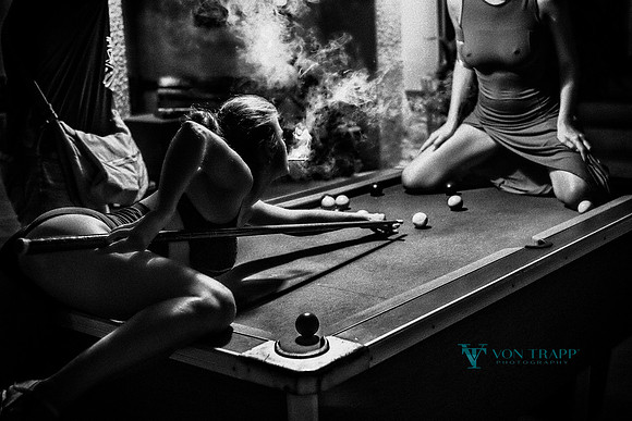 Edgy and erotic photo of two women on a pool table.