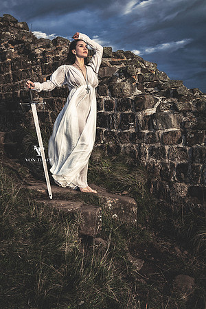 Fine art photo of a sexy woman at Hadrian's Wall, dressed in a period Celtic shift holding a broad sword.