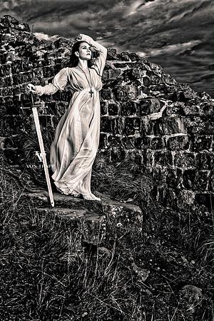 Fine art photo taken at Hadrian's Wall of a busty woman holding a broadsword ,dressed in a see-through white shift .