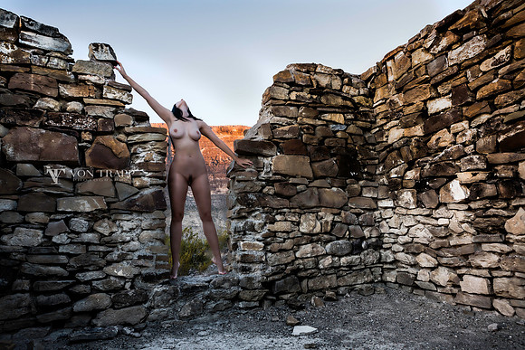 Art photo of a nude woman in the Texas desert, standing in the doorway of an old stone building.