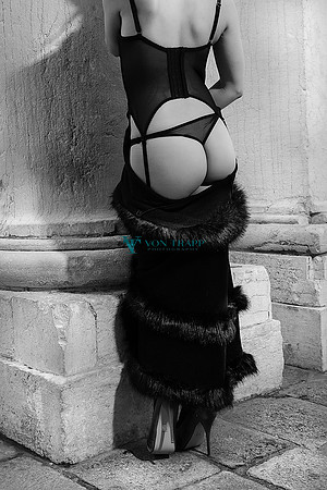 Fashion-glamour photograph of a model in lingerie and stilettoes posed in public in Venice.