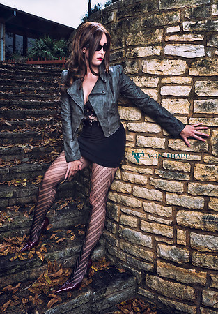 Sexy photo of a leggy woman in fashion tights, bustier, cropped leather jacket and stilettos.