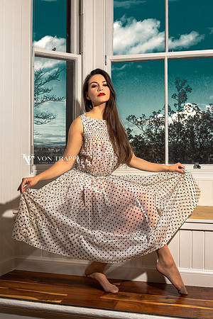 Fashion glamour photograph of a sexy woman in a sheer dress, bullet bra, and stockings.