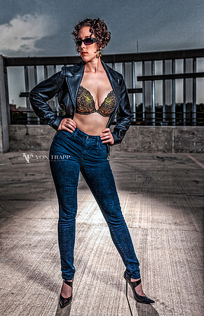 Fashion-Glamour photo of a voluptuous woman in tight jeans, bra, leather jacket and 5 inch fuck-me stilettoes.