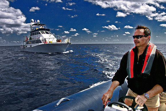 Photo of a man driving a rigid inflatable boat at sea.